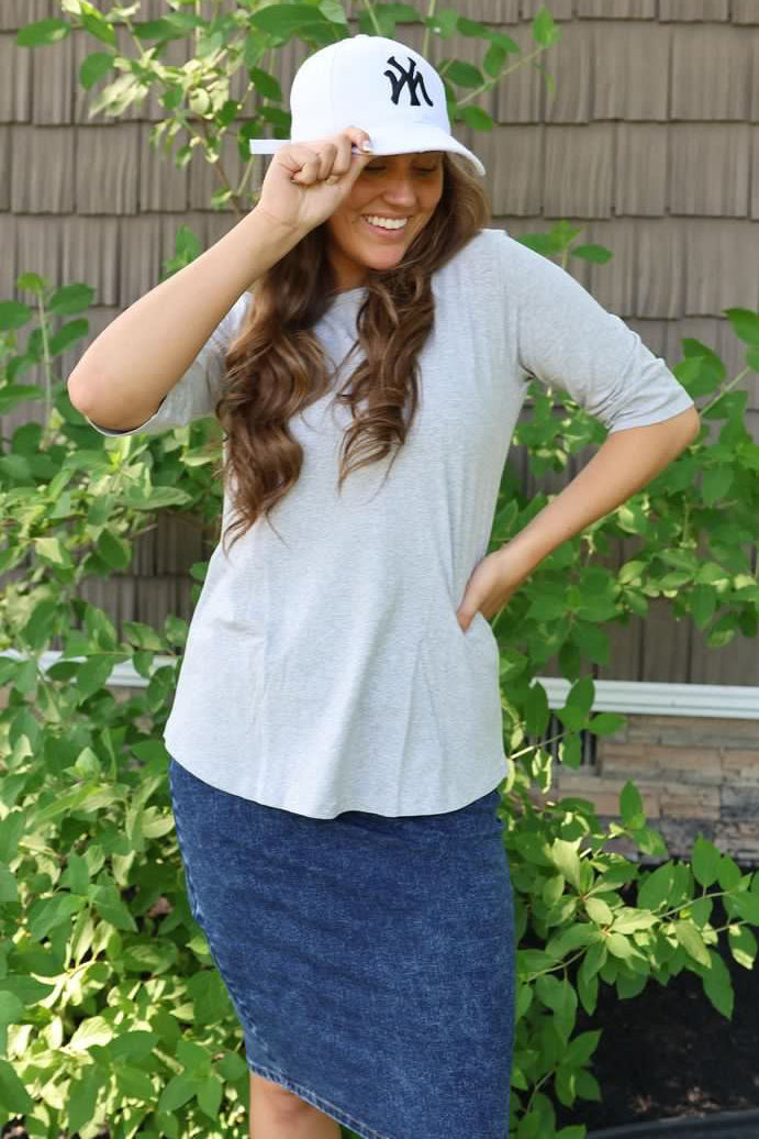 woman wearing a grey tunic top and a denim jean skirt